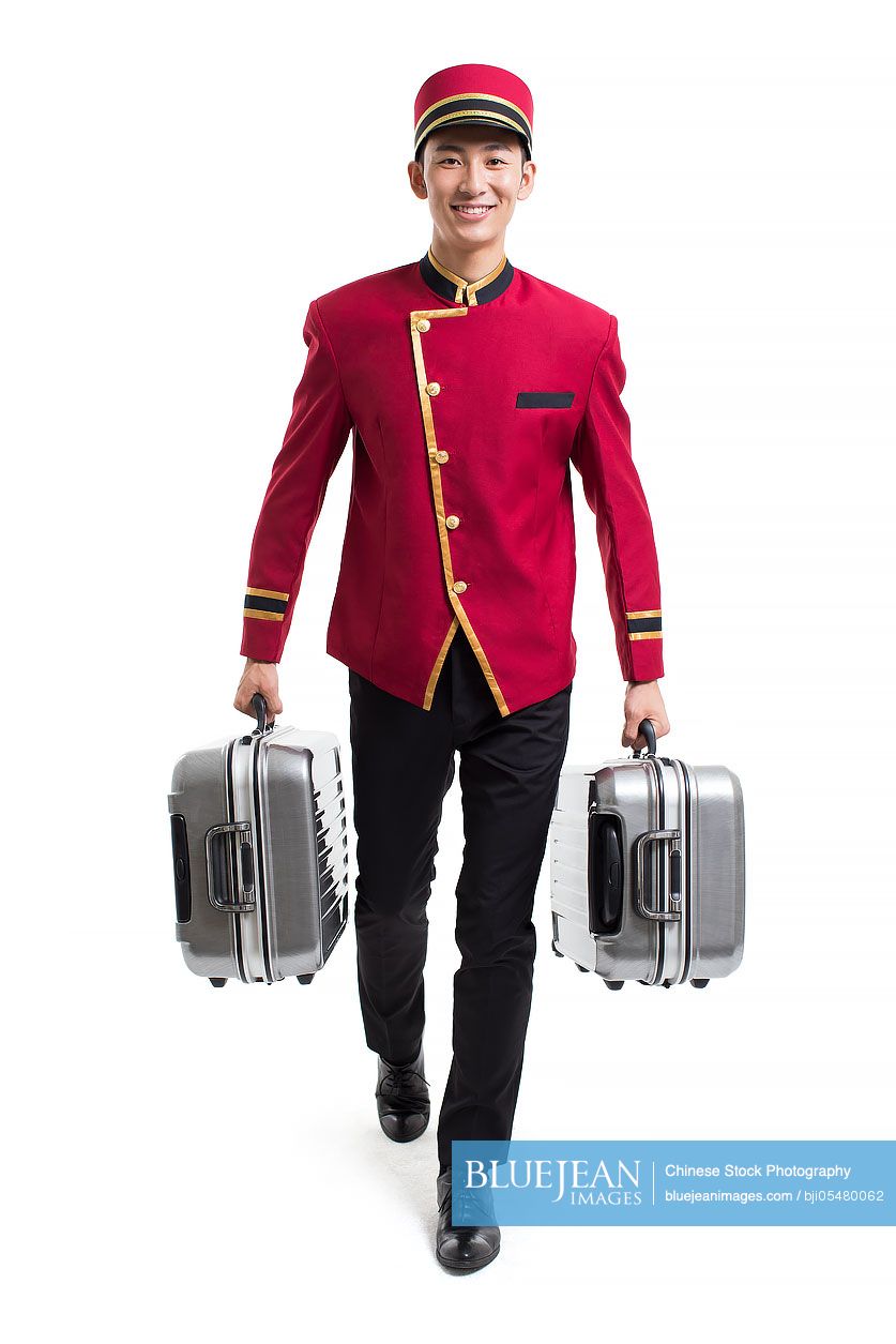 Young Chinese bellboy carrying suitcases