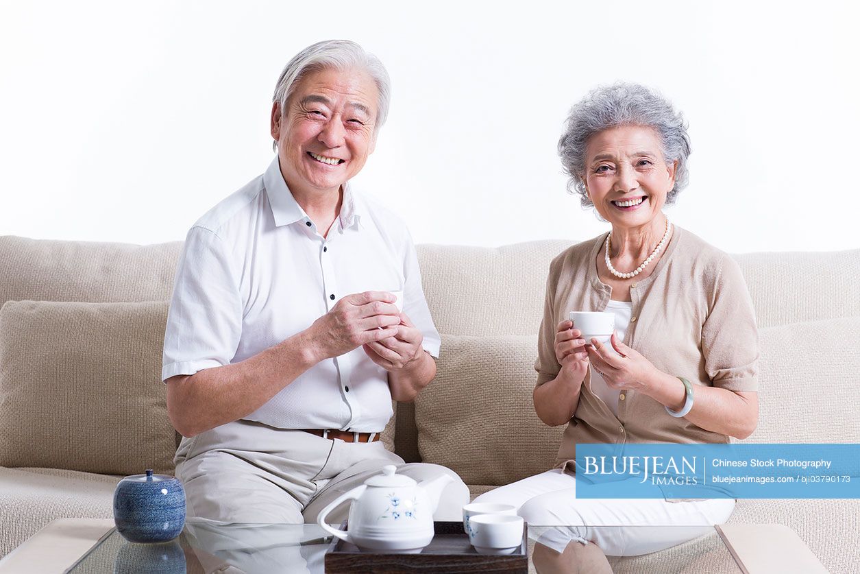 Cheerful senior Chinese couple having tea