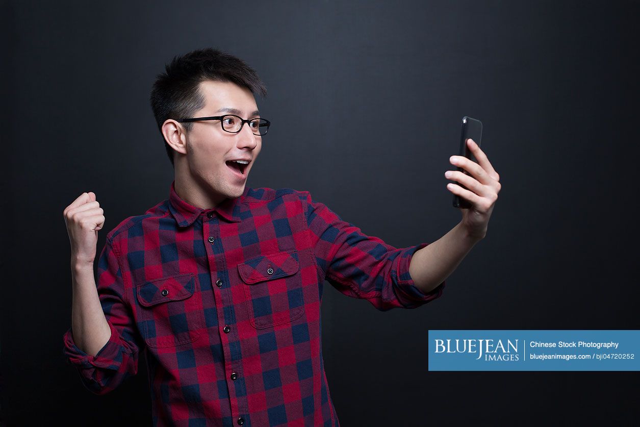 Excited Chinese man holding a smart phone