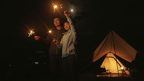 Happy Chinese couple holding sparklers and camping outdoors,4K