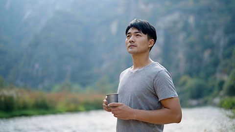 Cheerful young Chinese man enjoying the beautiful natural scenery