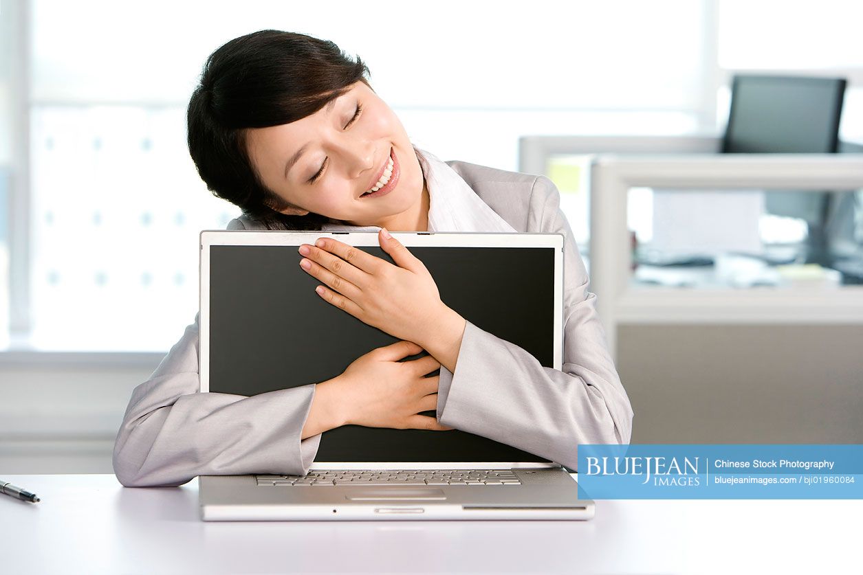 Chinese office worker hugging her computer