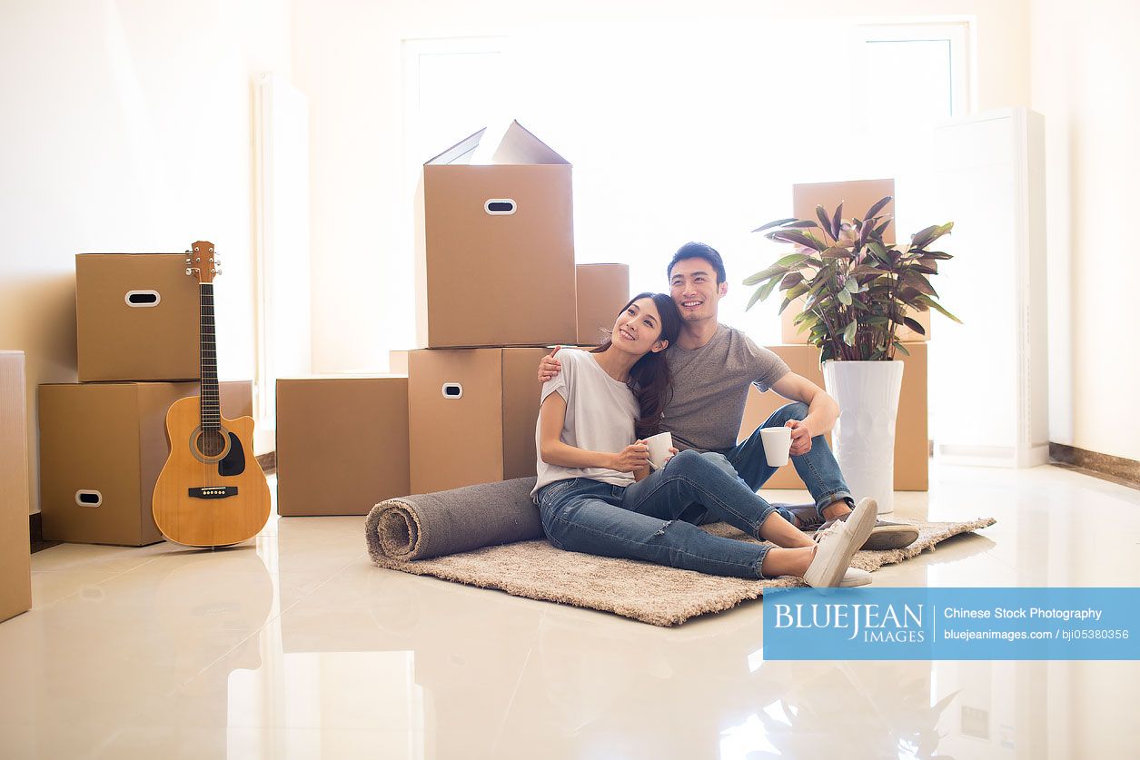 Happy young Chinese couple moving to a new house
