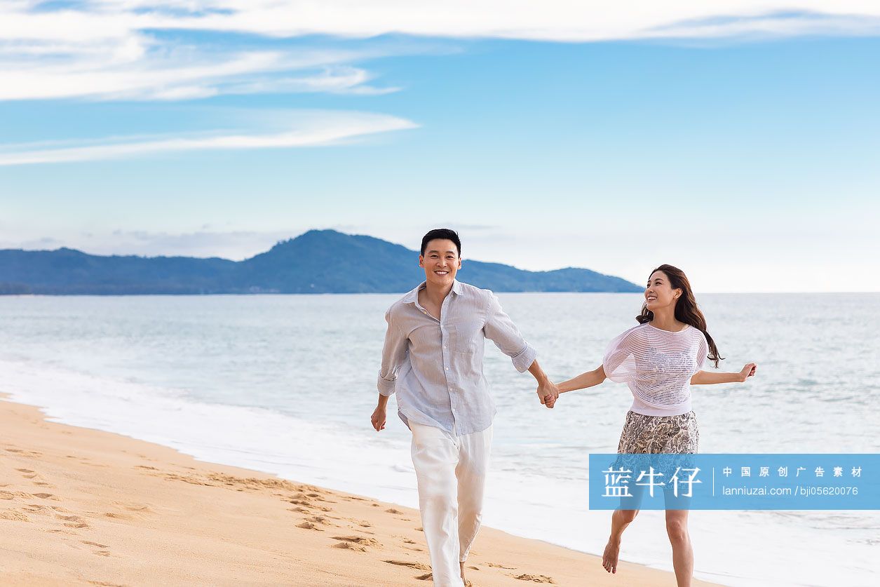 快乐的年轻夫妇在沙滩奔跑