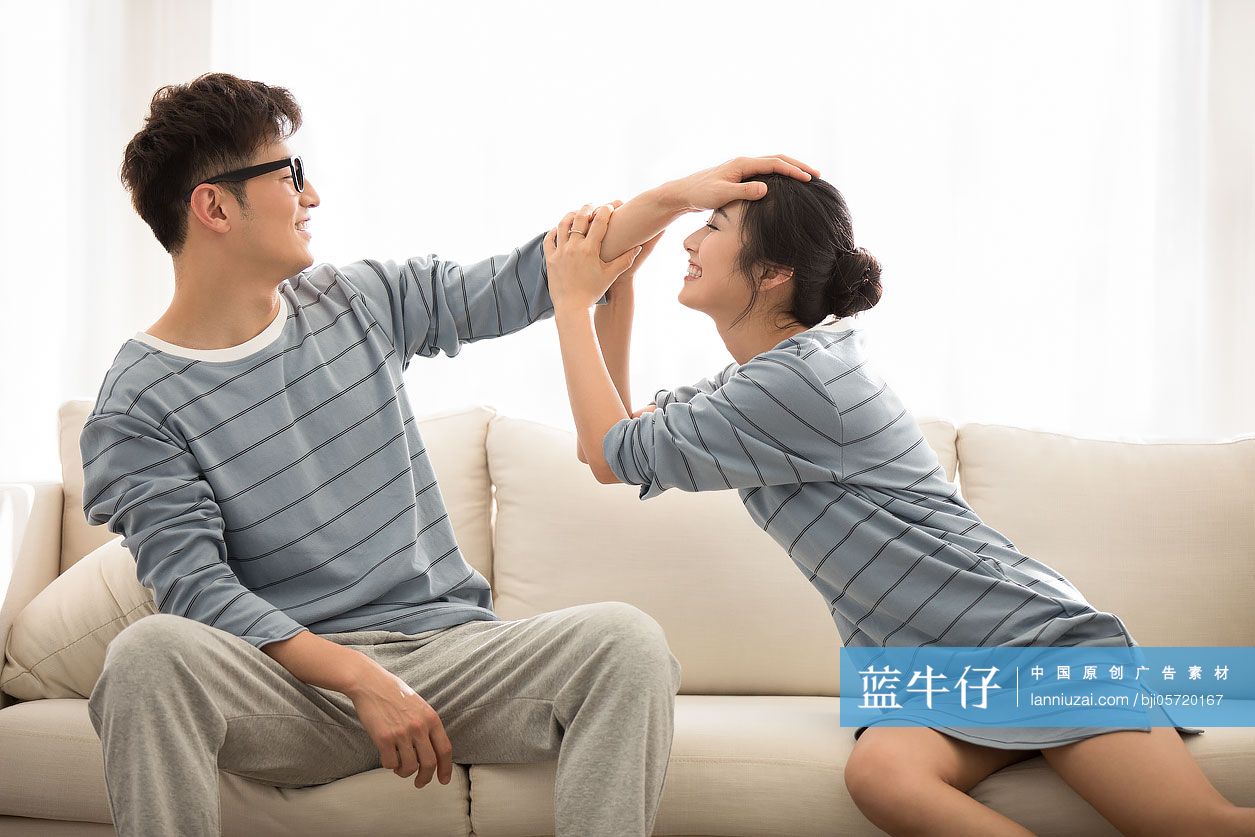 快乐年轻情侣在沙发上打闹