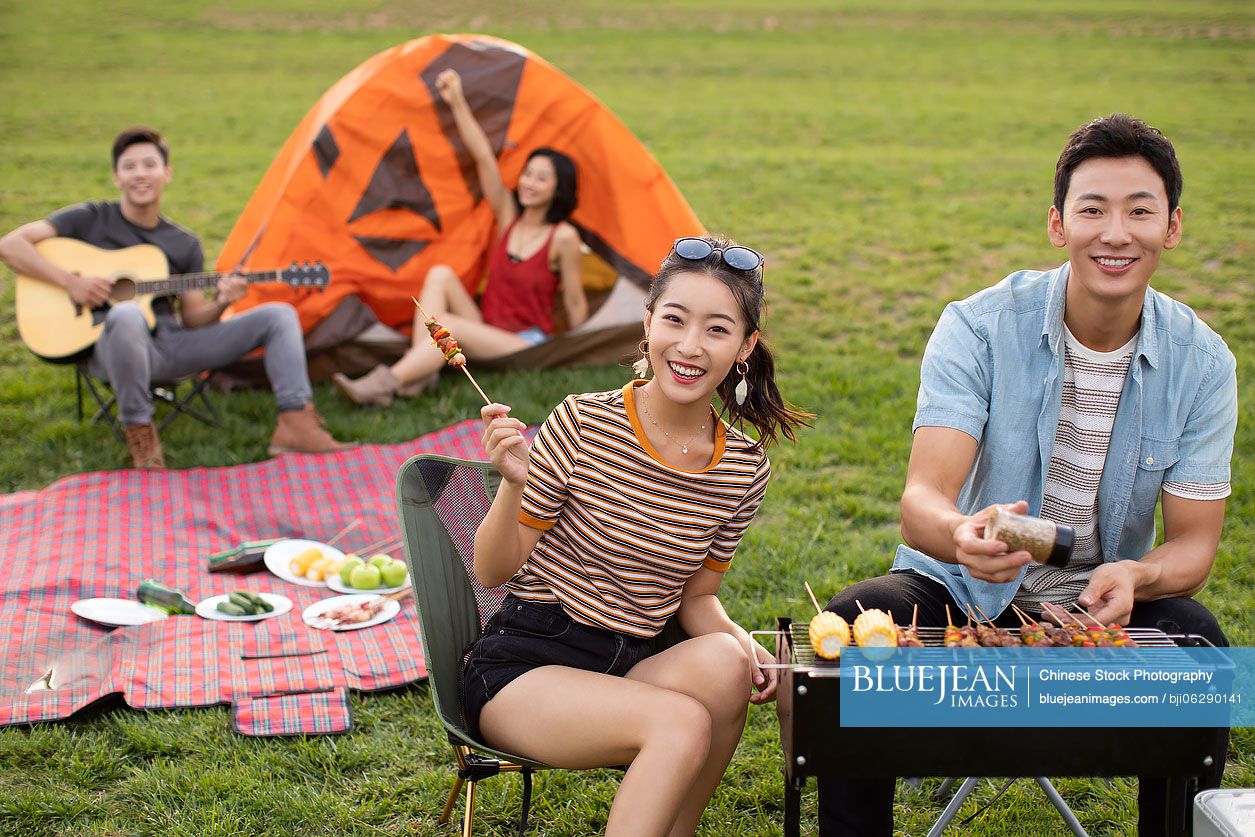 Happy young Chinese friends barbecuing outdoors