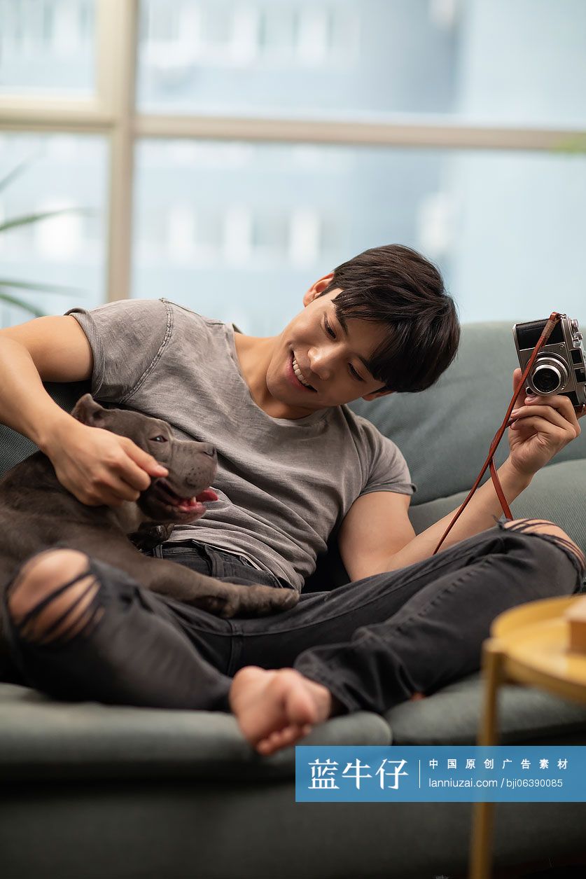 年轻男士和宠物狗在沙发上