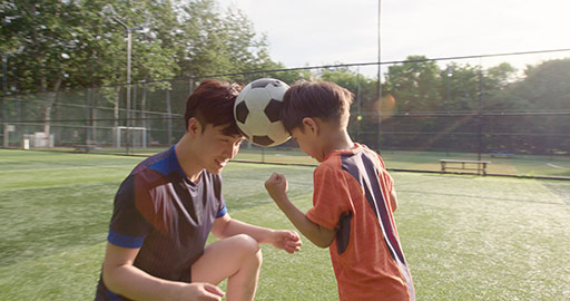 Chinese father and son playing football on soccer field,4K