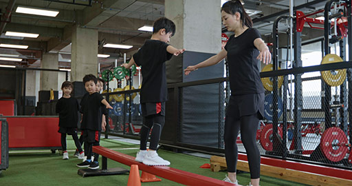 Active Chinese children having exercise class with their coach in gym,4K