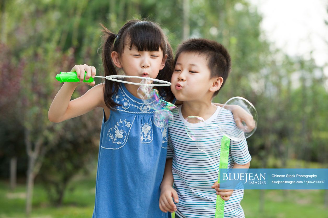 Two Chinese children blowing bubbles