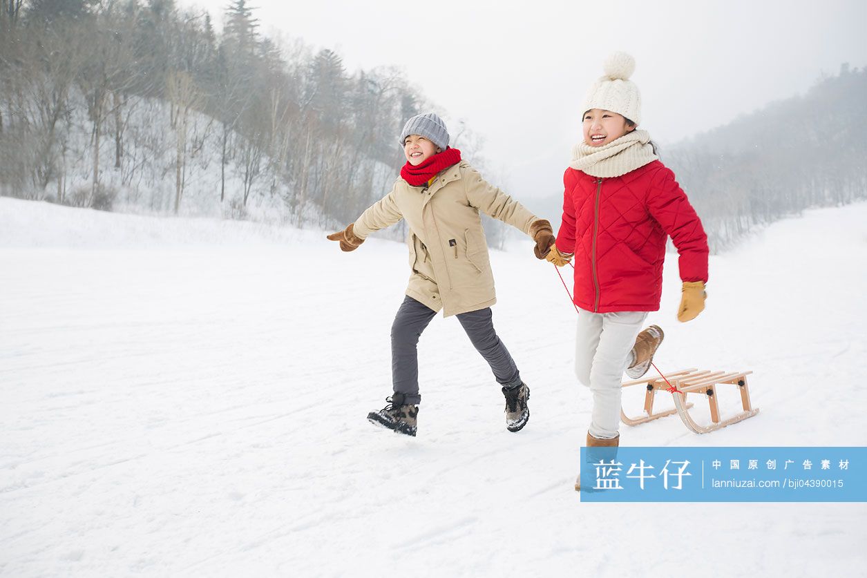 快乐的小孩在雪地上拉着雪橇奔跑
