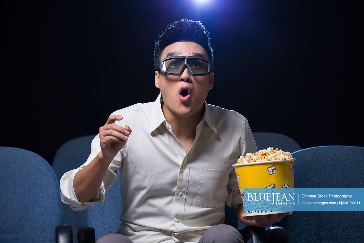 Young Chinese man watching 3D movie in cinema