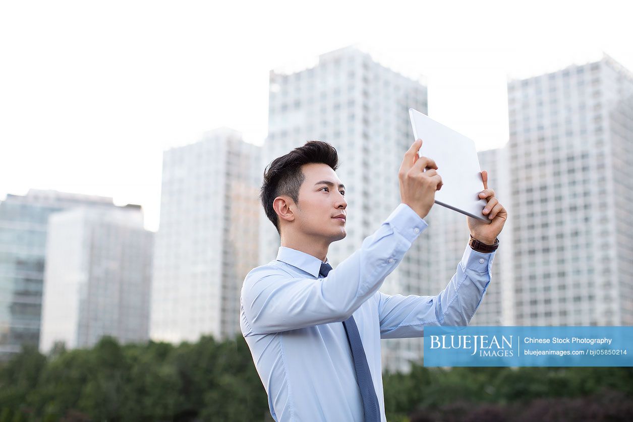 Young Chinese businessman using digital tablet