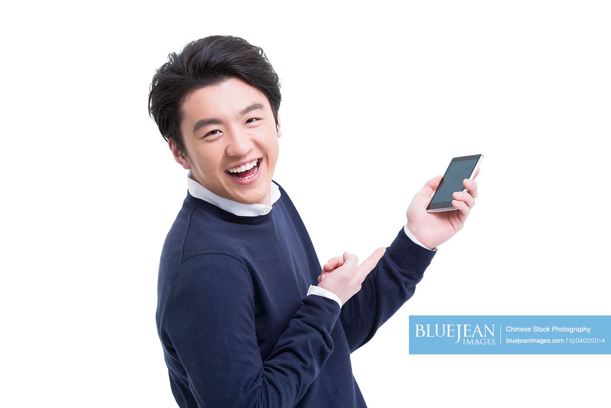 Cheerful young Chinese man with mobile phone in hand