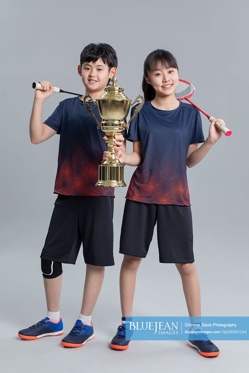 Cheerful Chinese girl and boy showing trophy