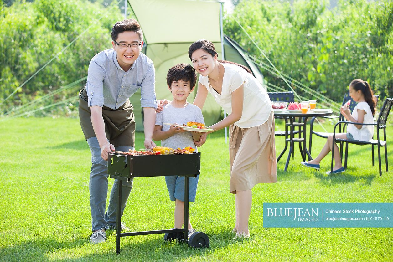 Young Chinese family barbecuing outdoors