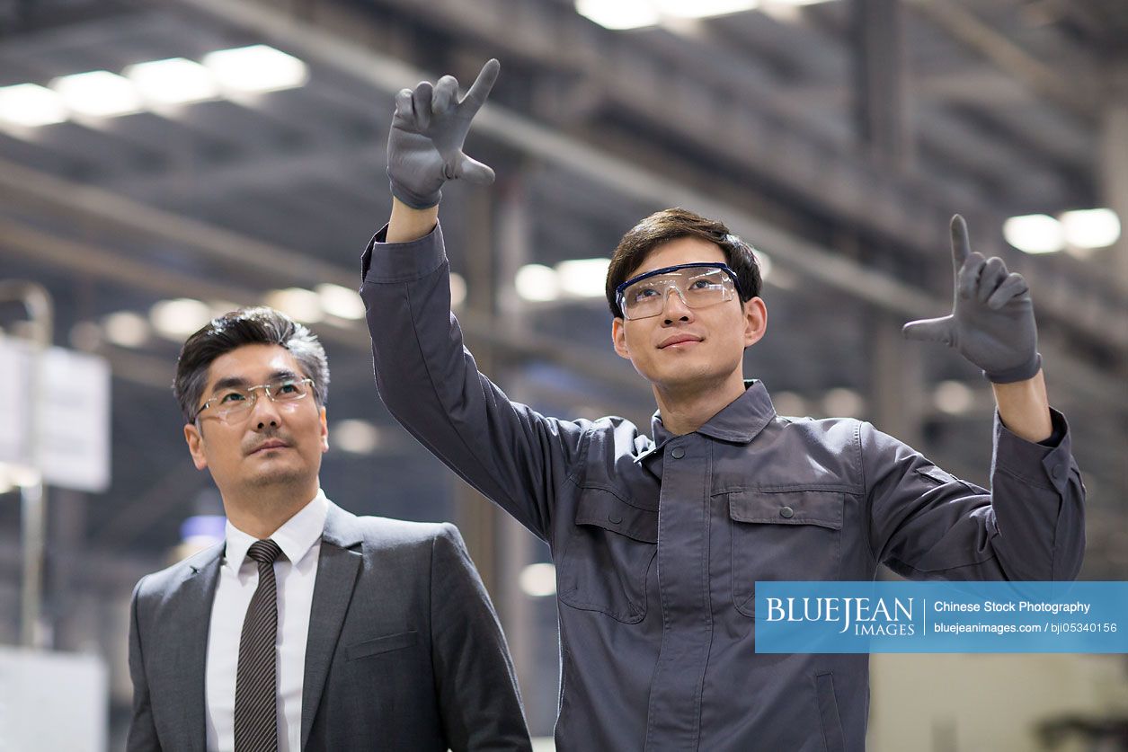 Chinese businessman and engineer talking in the factory