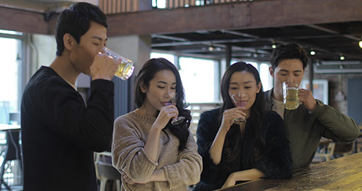 Happy young Chinese friends having drinks and talking at bar,4k