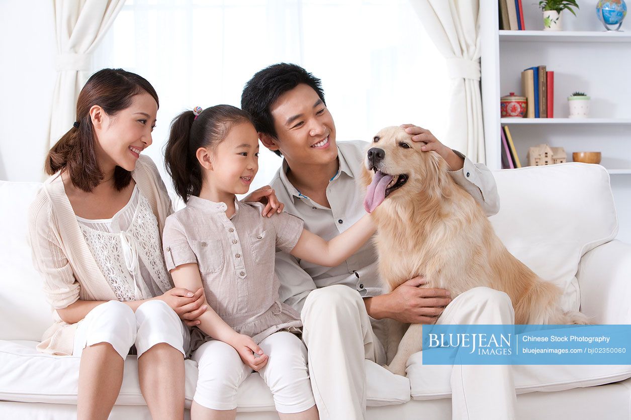 Happy Chinese family and dog on sofa
