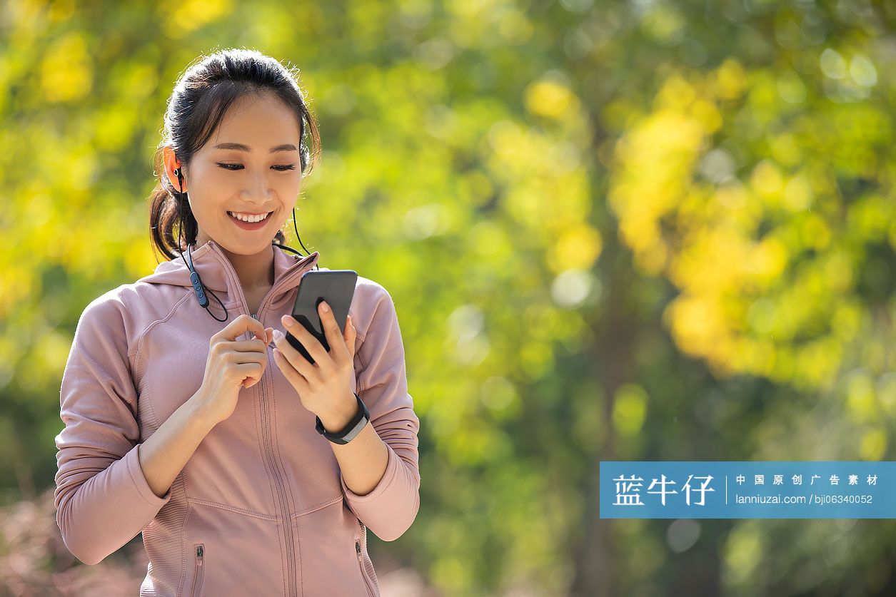 年轻女士在公园健身后使用手机