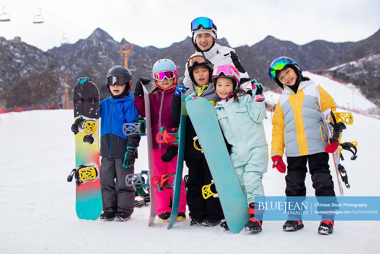 Cheerful Chinese children with their coach in ski resort