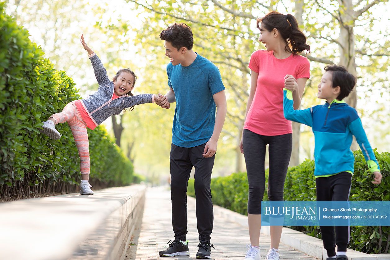 Happy young Chinese family playing in park
