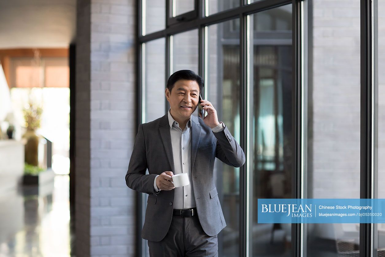 Confident Chinese businessman talking on cell phone