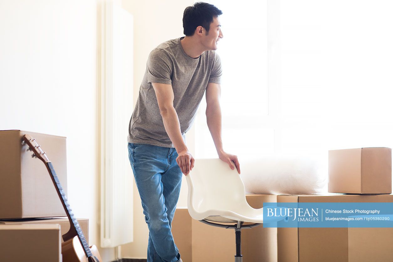 Happy young Chinese man moving to a new house