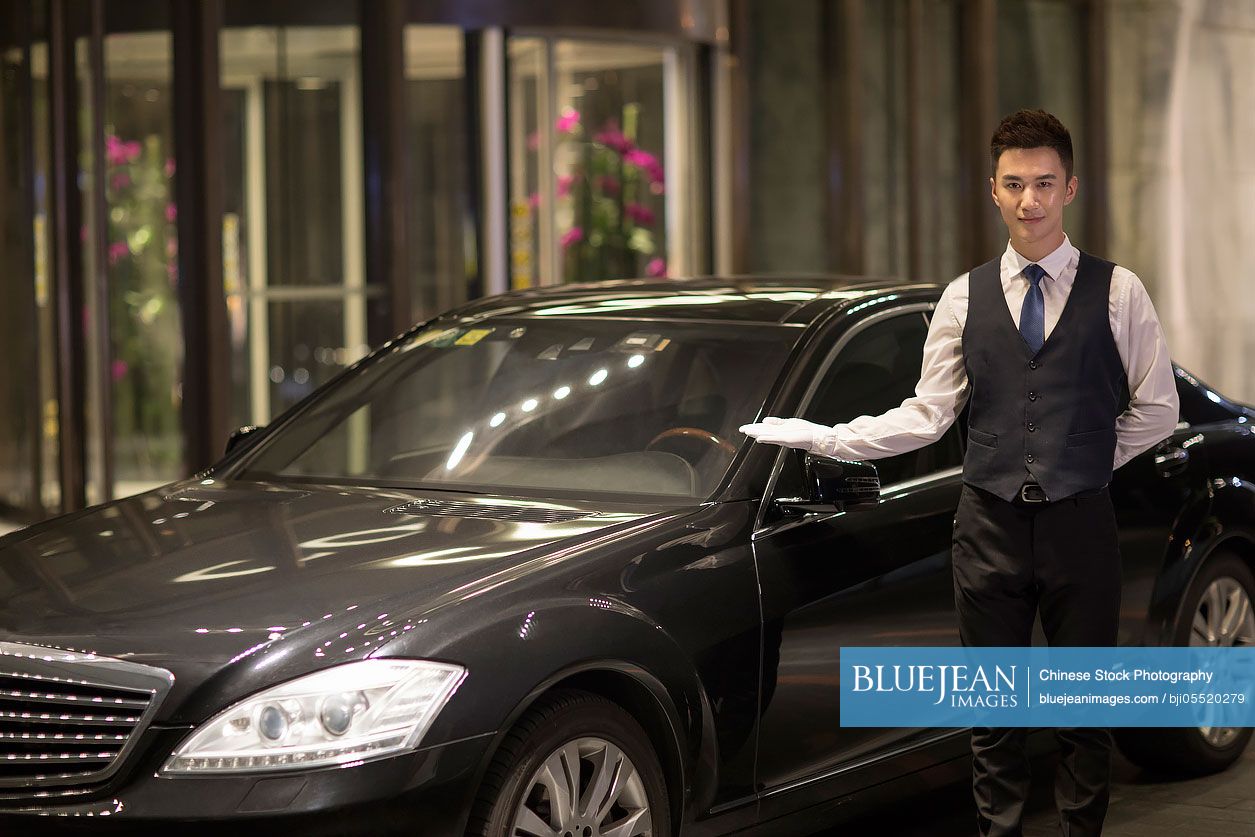 Chinese chauffeur standing next to the car