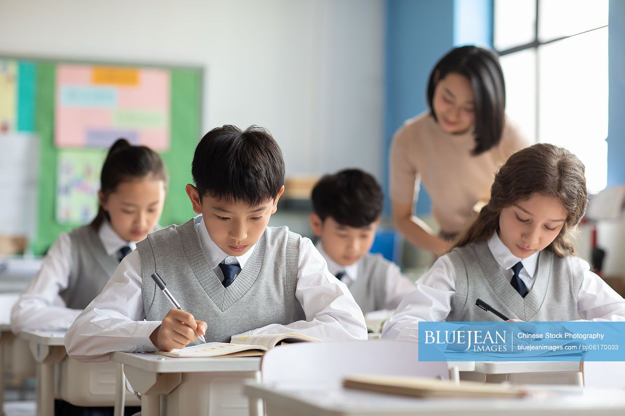 Young Chinese teacher helping students in classroom