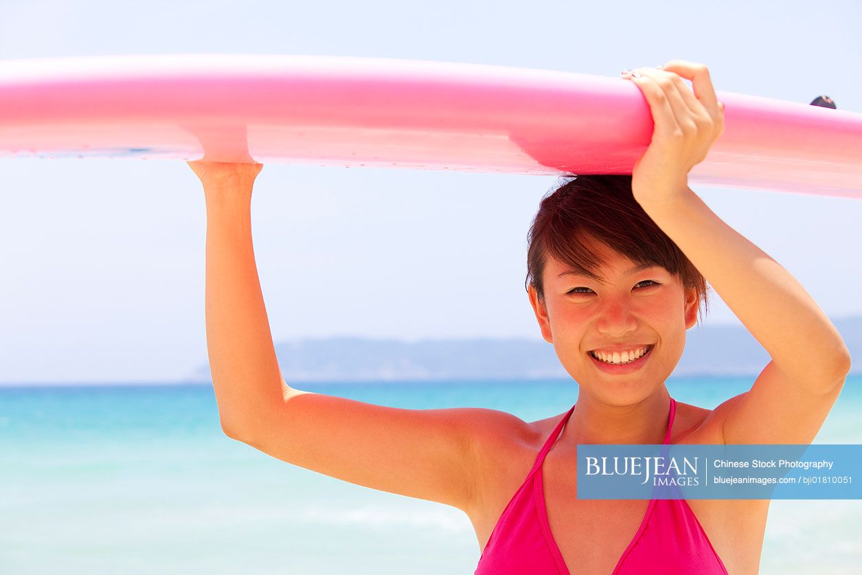 Portrait of a young Chinese woman with a surfboard