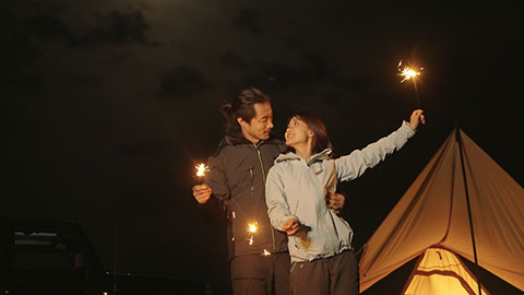 Happy Chinese couple holding sparklers and camping outdoors,4K