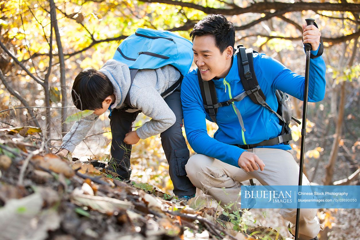 Cheerful Chinese father and son hiking in woods