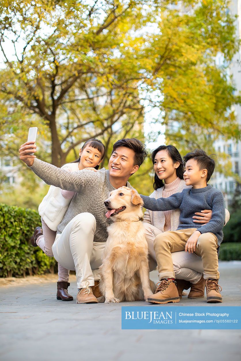 Happy young Chinese family taking a selfie with their dog