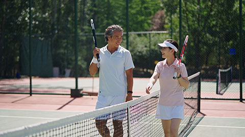 Mature Chinese couple playing tennis ball