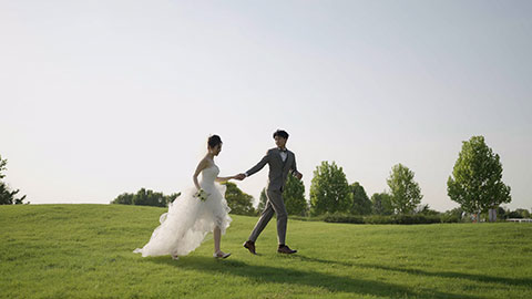 Happy bride and groom running on grass