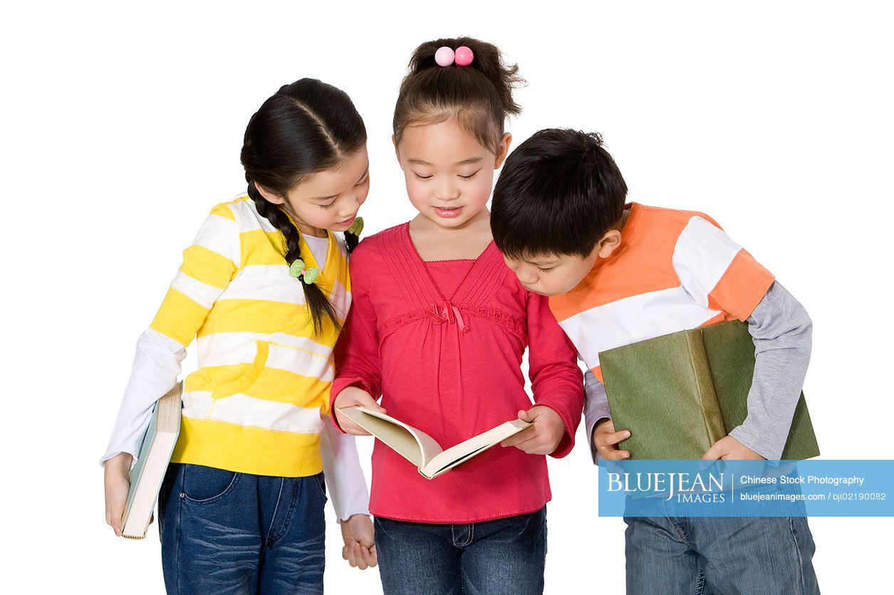 Three Chinese classmates looking at a book together