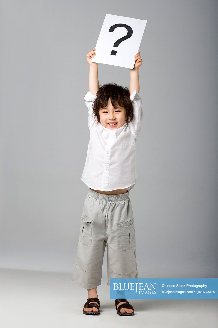 Little Chinese boy holding a sign with a question mark