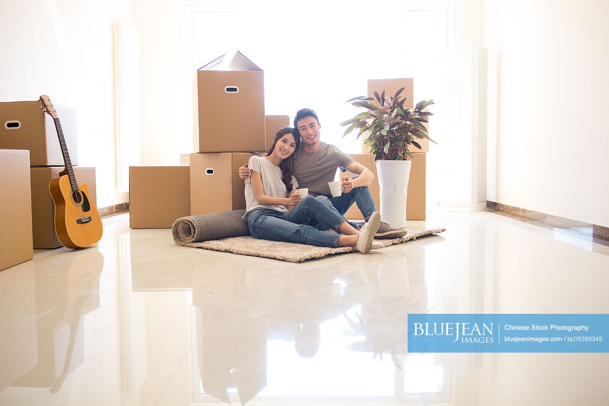 Happy young Chinese couple moving to a new house