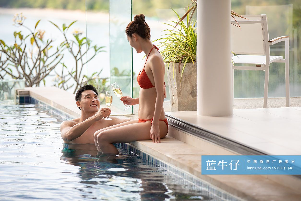 快乐的年轻情侣在泳池边喝香槟