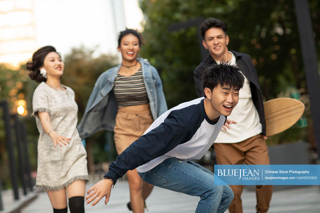 Fashionable young Chinese people enjoying skateboarding outdoors