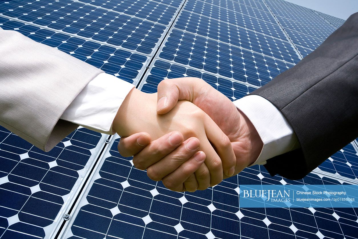 Handshake in front of solar panels