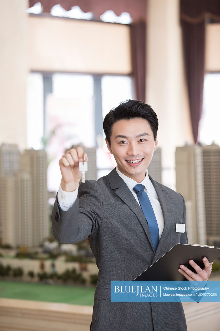 Confident Chinese realtor holding house keys