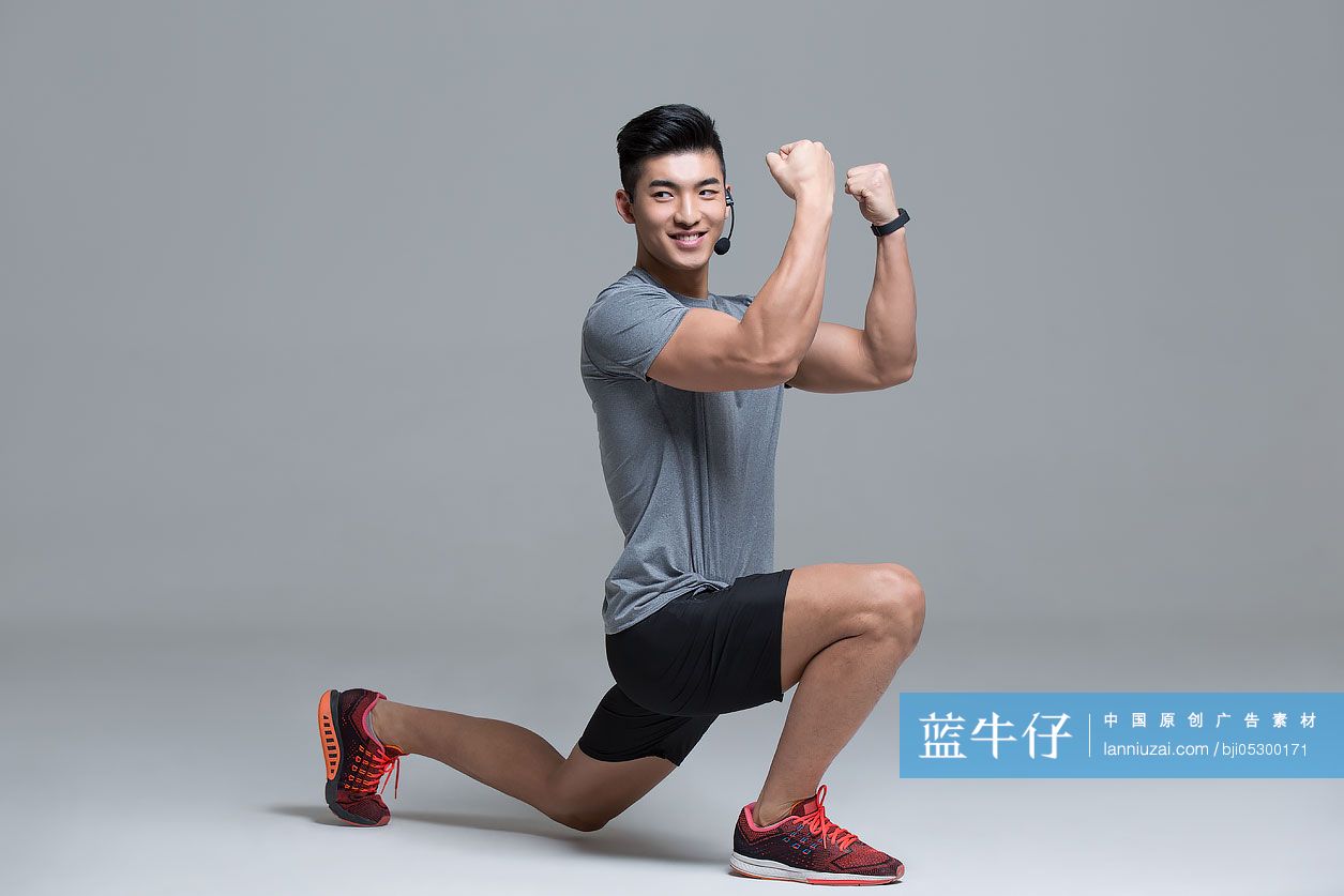 佩戴耳麦的快乐男教练在健身房授课