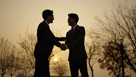 Confident Chinese businessmen shaking hands outdoors