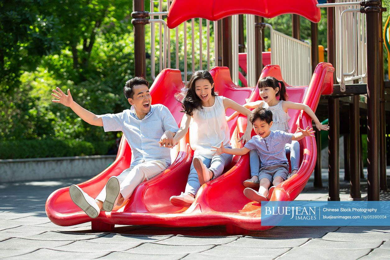 Happy young Chinese family playing in amusement park