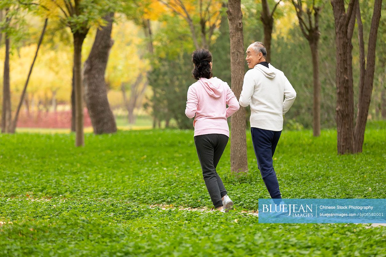 Happy senior Chinese couple running in the park