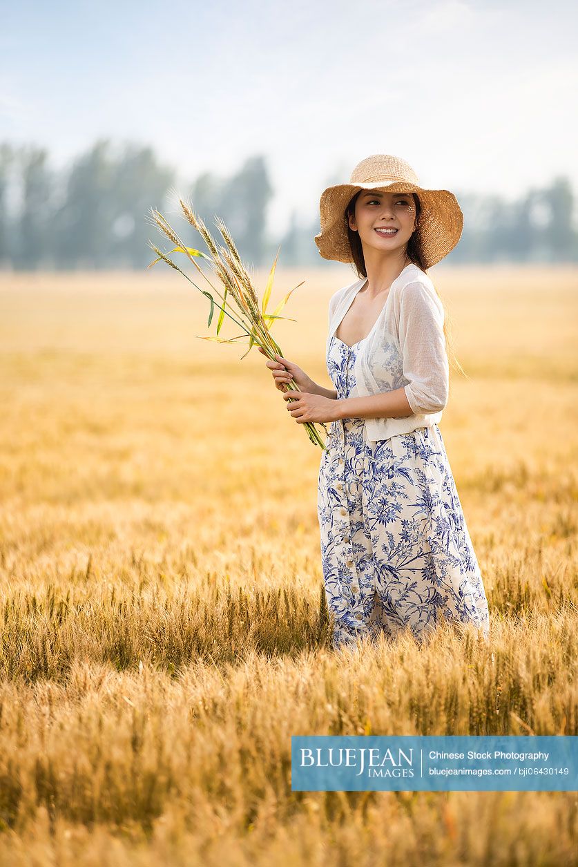 Happy young Chinese woman in wheat field