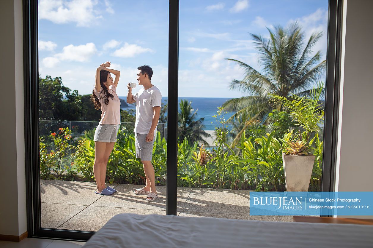 Happy young Chinese couple relaxing on balcony