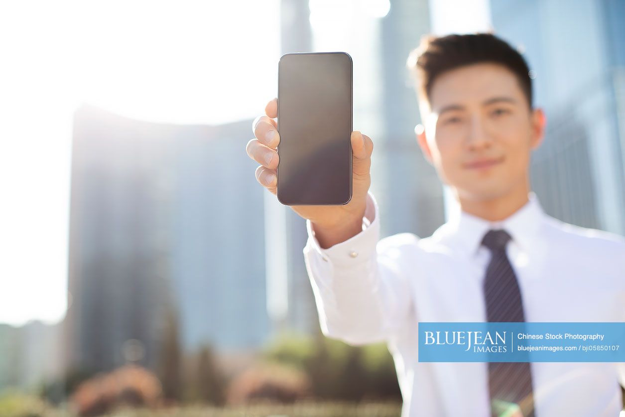 Young Chinese businessman showing the smart phone